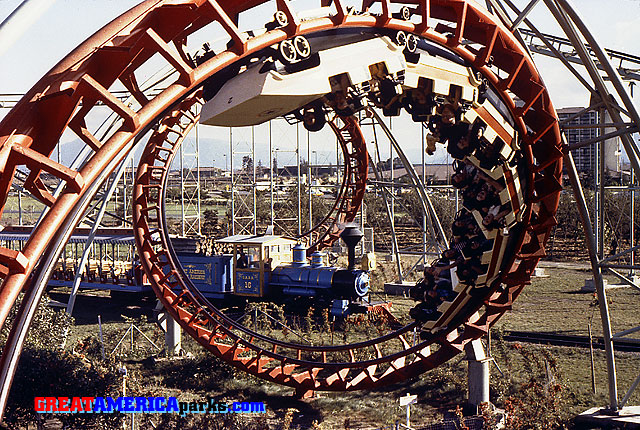 corkscrew and train
Santa Clara, CA -- 1979
The GREAT AMERICA Scenic Railway train passes through the corkscrew element of the [i]Turn of the Century[/i] roller coaster. The Santa Clara Marriott hotel is in the background on the right.
